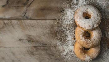Copy Space image of Donuts with powdered sugar on wooden table on black background photo