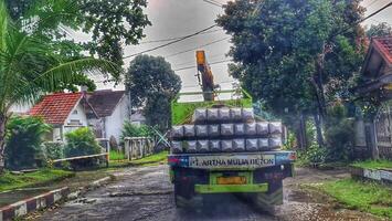 Bekasi, Indonesia on October 7, 2023. A small flat bed truck is transporting a pile of square pile or minipile material.. photo