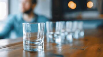 Wide shot of a person at a bar with multiple empty glasses, indicating alcohol addiction photo