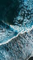 Waves crashing on a sandy beach, seen from above photo