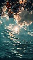 Sunbeams shimmer through the water, illuminating clouds above photo