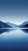 A still lake reflecting a mountain range under a clear, blue sky photo