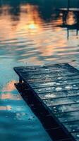 A wooden dock juts out into a still lake at sunset photo