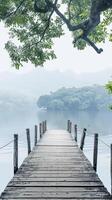 Wooden dock on serene lake, shrouded in mist, reaches tranquil island photo