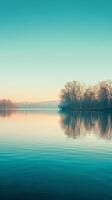 A serene lake with a sliver of trees reflected in the water photo