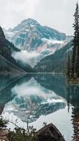 A serene lake reflects the majestic mountains and clouds in a picturesque scene photo