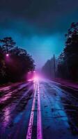 A wet road stretches into the distance with fog and neon lights photo