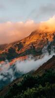 Golden clouds paint the sky as fog drifts over a mountainside photo