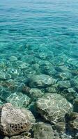 Sunlit water reveals smooth stones on the bottom of a calm sea photo