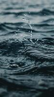 Closeup of a water droplet splashing on a dark blue water surface photo