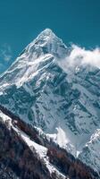 A snow-covered mountain peak dominates the landscape under a clear blue sky photo