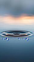 A single drop creates concentric circles on still water photo
