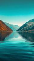 A serene lake reflecting the surrounding mountains under a clear blue sky photo