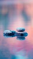 Three stones balanced on a still lake reflecting the vibrant colors of a setting sun photo