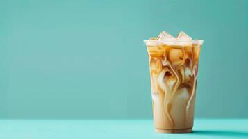 A glass of iced coffee with cream and ice cubes sits on a blue surface photo