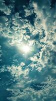 Bright sun shining through white puffy clouds photo