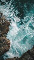 Foamy ocean waves crash against jagged rocks photo
