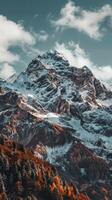 A snow-capped mountain peak rises under a cloudy sky photo