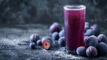 A glass of prune juice with plums on a dark countertop photo