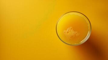 A glass of pineapple juice sits on a yellow surface photo