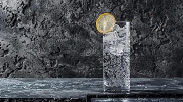 Tall glass of club soda with lemon and ice on dark surface photo