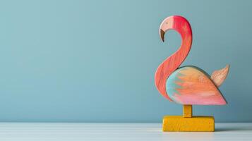 Colorful wooden flamingo on yellow stand against light blue background photo