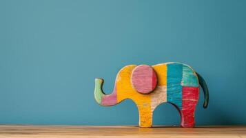 A colorful wooden elephant toy sits on a desk against a blue wall photo