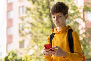 Portrait of teen boy using smartphone. Blogging, surfing, call. Generation z, mobile generation. Low angle view, copy space. photo
