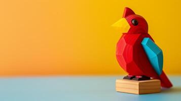 A bright red wooden Cardinal toy sits on a desk with a yellow and blue backdrop photo
