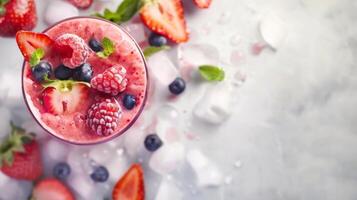 A glass of berry smoothie with fresh fruit and ice on a white surface photo