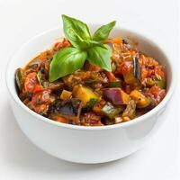 Close-up of white bowl with colorful ratatouille, garnished with basil photo