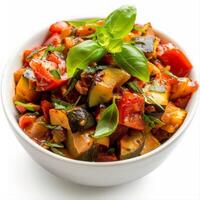 A bowl of ratatouille, a classic French vegetable stew, garnished with fresh basil leaves photo