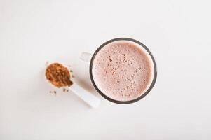 Close up of healthy chocolate protein drink in a glass and powder in a jar on the table top view photo