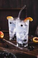 Refreshing lemonade with blackcurrant, nectarine and ice in glasses on the table vertical view photo