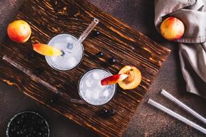 Refreshing lemonade with blackcurrant, nectarine and ice in glasses on the table top view photo