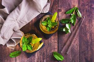 Refreshing iced tea with mint and lime in glasses on the table top view photo