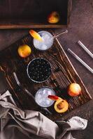 Ice cocktail with blackcurrant and nectarine in glasses on the table top and vertical view photo