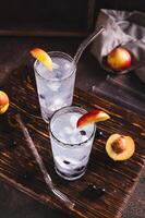 Ice cocktail with blackcurrant and nectarine in glasses on the table vertical view photo