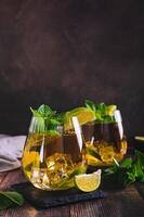 Refreshing iced tea with mint and lime in glasses on the table vertical view photo