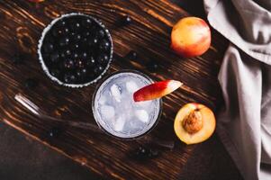 Close up of lemonade with blackcurrant, nectarine and ice in glasses on the table vertical view photo