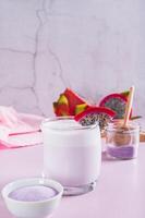 Trendy pink matcha dragon fruit latte in a glass on the table vertical view photo
