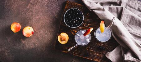 Ice cocktail with blackcurrant and nectarine in glasses on the table top view web banner photo
