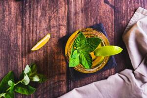 Close up of refreshing iced tea with mint and lime in a glass on the table top view photo