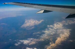 Clouds and mountains below, view from an airplane window photo