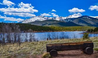 A tree trunk bench against the backdrop of the snow-capped Pikes Peak mountains, Colorado, US photo