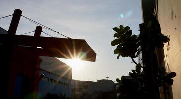 Sun lights beam between building structure silhouette isolated on horizontal ratio outdoor environment background. photo