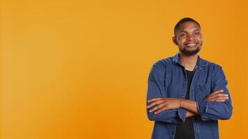 Portrait of african american casual man posing against orange background, showing confidence and determination in studio. Charismatic serious guy in stylish clothes. Camera B. photo