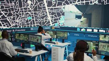 Diverse employees operators tracking delivery cars on satellite navigation map, guiding couriers in the city to avoid traffic and get to the destination. Shipping agency delivering cargo. Camera B. photo
