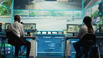 Diverse employees working on examining real time surveillance footage to find irregularities within urban traffic dynamics. Agency workers monitoring on CCTV system for intelligence. Camera B. photo