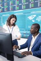 Enterprise colleagues reviewing project updates and details in monitoring room, establishing budget and other resources to achieve strategic business goals. Multiple corporation operations. photo